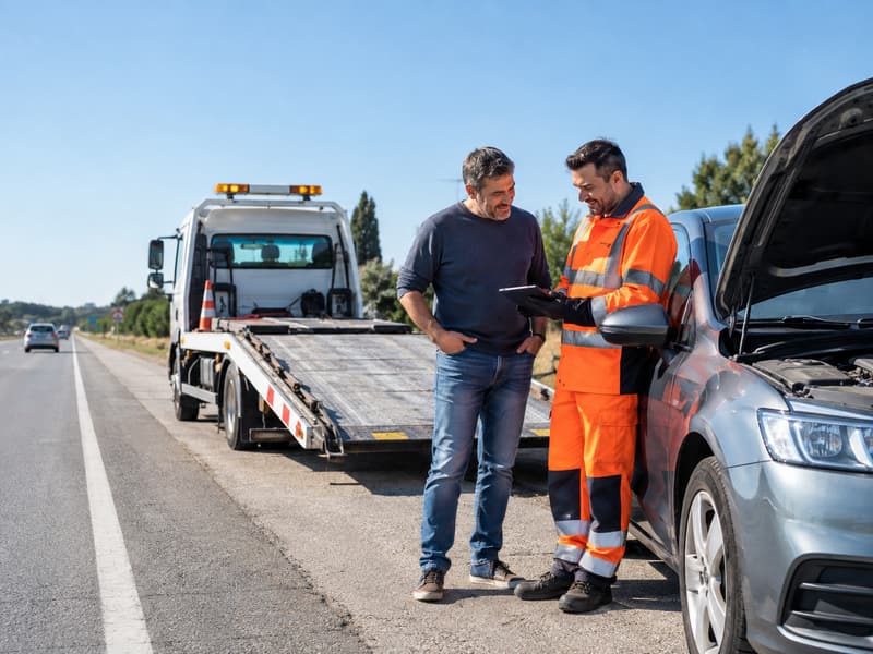 Chofer de grúa asistiendo a un conductor en la ruta